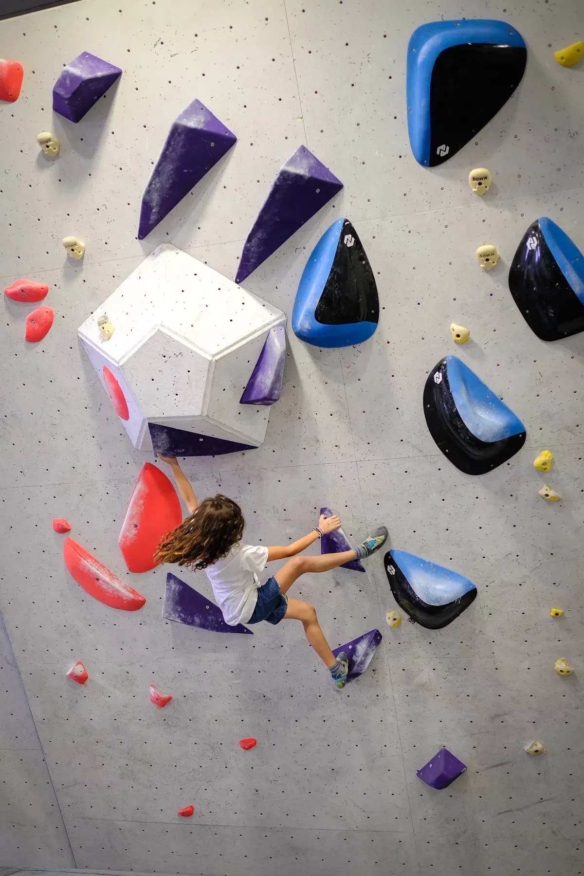Niña escalando un bloque con volúmenes
